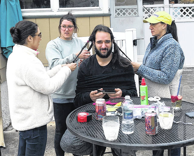
			
				                                Leo Malsky sits while his sisters Aly, right, Anna, center, and mother, Gina, braid his hair just before his Gina did the honors of cutting it.
                                 Submitted photo

			
		