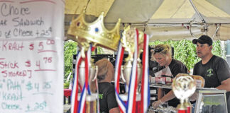 
			
				                                Bill Cost, seen through prior years’ trophies won by Bosak’s, takes an order for kielbasa during the Plymouth Alive Kielbasa festival in 2019. This year’s festival is set for Aug. 11-12.
                                 Times Leader file photo

			
		